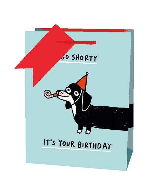 Blue gift bag with a cartoon sausage dog in party hat and with a streamer, text reads Go Shorty, It's your birthday