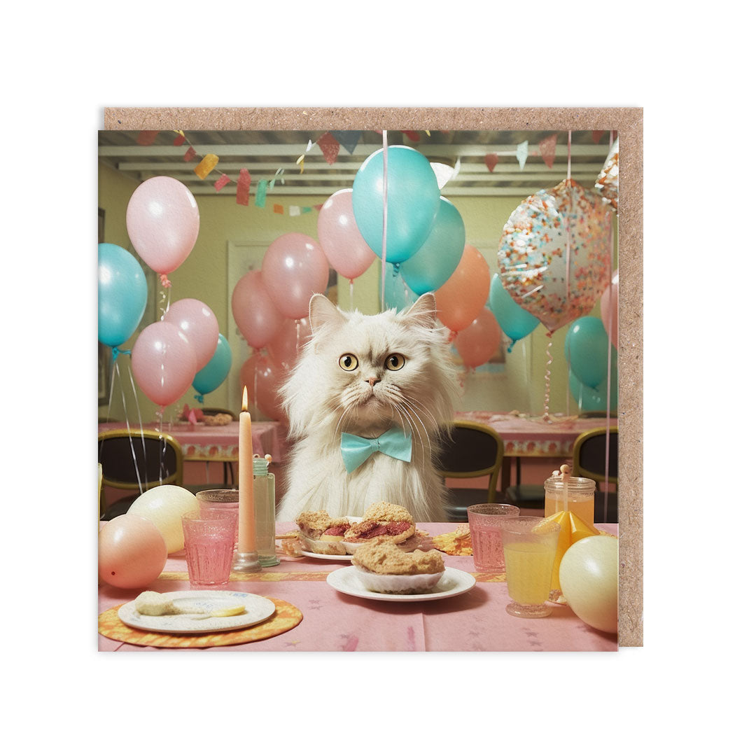 Birthday card with an image of a cat at a party table surrounding by balloons