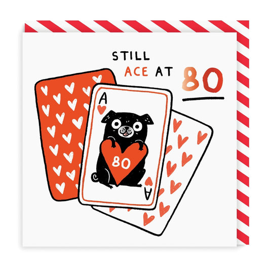 White birthday card with red and black illustrated playing cards and pug holding red heart, saying 'Still Ace at 80' wording